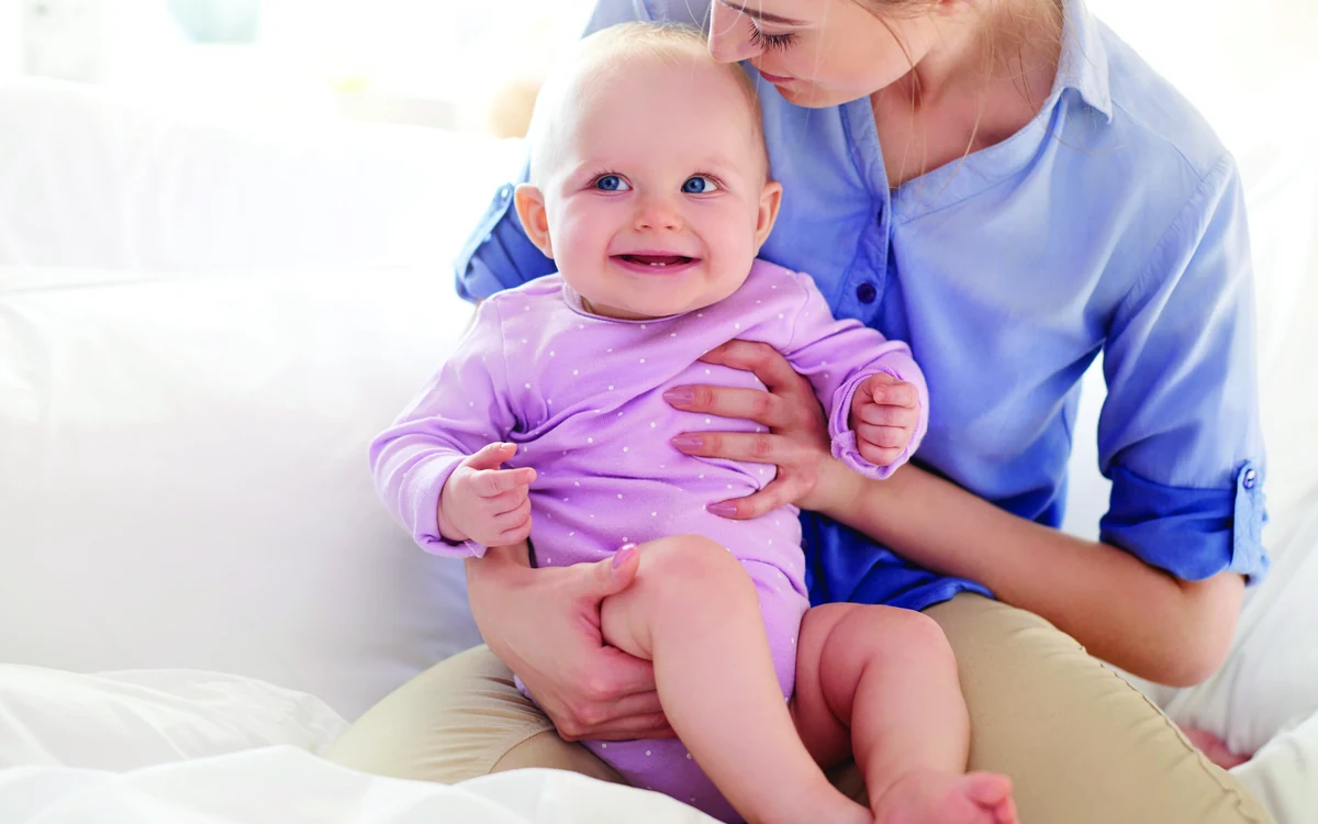 Bebé sonriendo en brazos de su madre